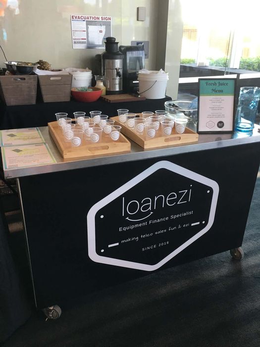 Loanezi branded fresh juice bar with wooden serving trays and Fresh Juice Menu sign at a corporate event